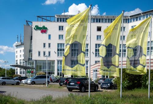 un grupo de banderas amarillas frente a un edificio en SleepBEEONE AIRPORTHOTEL FRANKFURT MÖRFELDEN, en Mörfelden-Walldorf