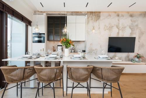a kitchen with a large white island with chairs at Sol Marina Resort Wyspa Sobieszewska I - LoftAffair Collection in Wiślinka
