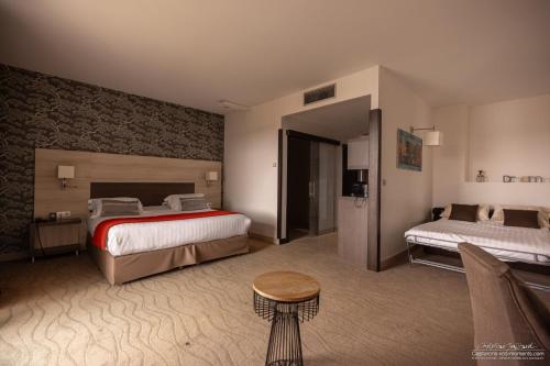 um quarto de hotel com duas camas e uma mesa em Kyriad Prestige Lyon Est - Saint Priest Eurexpo Hotel and SPA em Saint-Priest
