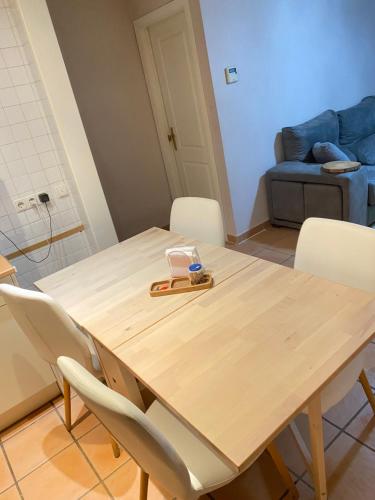una mesa de madera con sillas blancas en una habitación en Apartamento playa, en Islantilla
