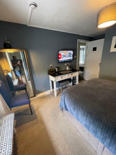 a bedroom with a bed and a desk and a television at Skyline Guesthouse in Newquay