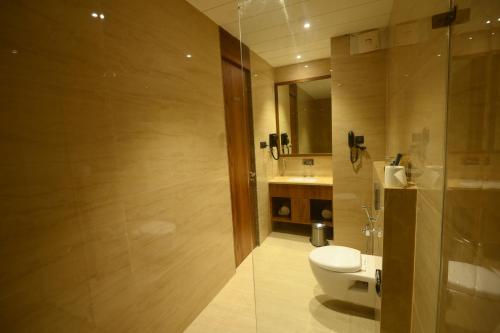 a bathroom with a toilet and a sink and a shower at Kings Kraft Tremezzo Inn, Somnath in Somnath