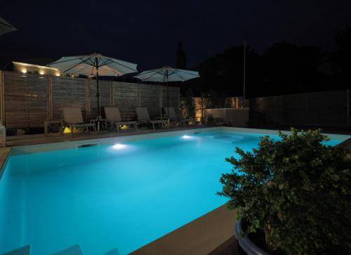 a swimming pool lit up at night with umbrellas at Erato by Vintage Travel in Tsoukaladhes