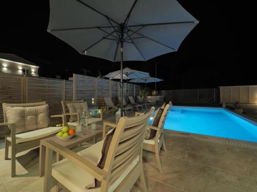 a dining table with an umbrella next to a pool at Erato by Vintage Travel in Tsoukaladhes