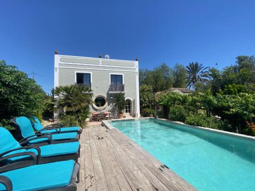 a villa with a swimming pool and chairs on a wooden deck at Casa Stardust & cottages in Quelfes