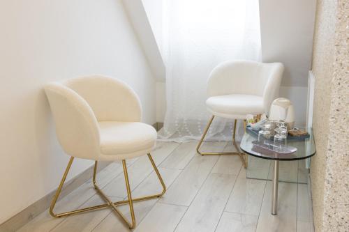 two white chairs and a table in a room at Mil Roses en Baie in Saint-Quentin-en-Tourmont