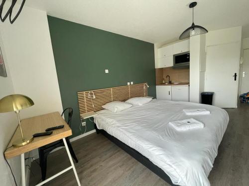 a bedroom with a large bed and a table and a desk at Bel appartement design tout confort (Parking Gratuit) à 10 minutes de Bordeaux in Cenon