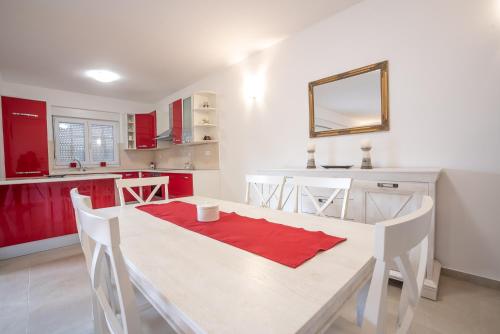 a kitchen with a white table and red cabinets at Sandrina Residences in Vrsi