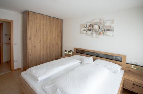 a bedroom with a white bed with a wooden headboard at Residence Sonneck in Martello
