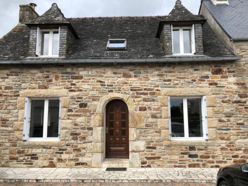 ceglany budynek z brązowymi drzwiami i trzema oknami w obiekcie Charmante maison en pierre w mieście Morlaix