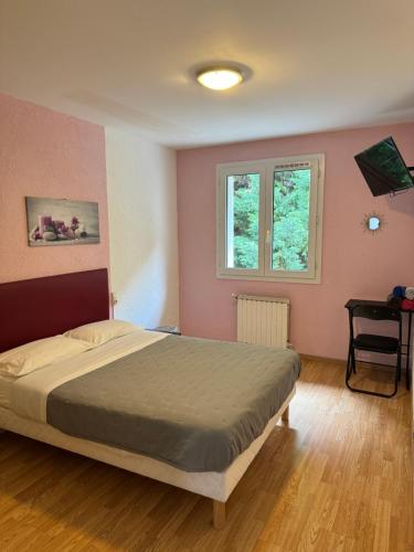 a bedroom with a bed with pink walls and a window at La Cascade in Onet le Château