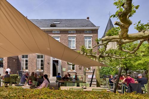 een groep mensen die aan tafels voor een gebouw zitten bij De Pastorie in Borgloon