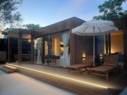 una terrazza esterna con due sedie e un ombrellone di 10gardens Premium Mobile Homes with private jacuzzi & sauna by OIKO Collection a Privlaka (Brevilacqua)