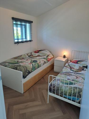 een slaapkamer met 2 bedden en een raam bij De Platwever 3B in Zelhem