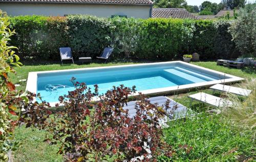 a swimming pool in a yard with two chairs in the grass at Villa La Coupe D'or in Avignon