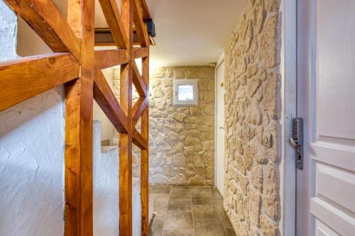 a hallway with a wooden door and a stone wall at La MaisondAbel in Le Bosc