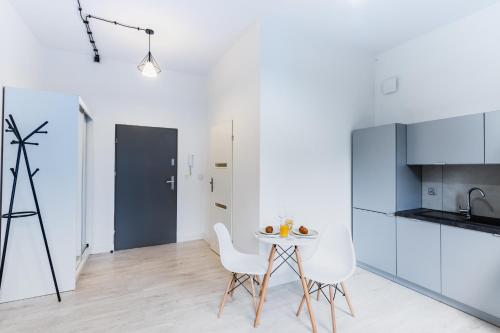 cocina con armarios blancos, mesa y sillas en Apartment Quiet Street 11/5E, en Oświęcim