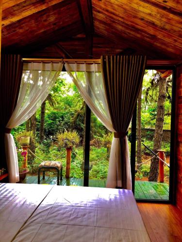 a bedroom with a bed and a large window at Pine Hill Villas & Camping in Sóc Sơn