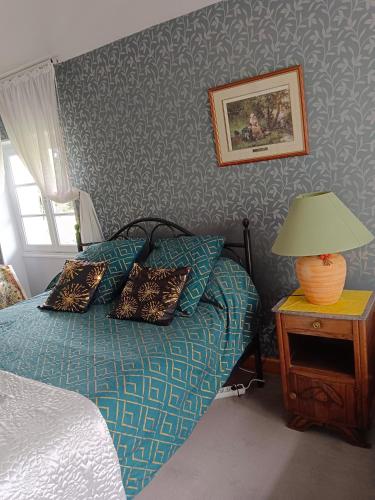 - une chambre avec un lit doté d'oreillers et d'une lampe dans l'établissement La maison basque, à Sainte-Livrade-sur-Lot