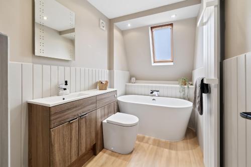 a bathroom with a toilet and a sink and a tub at CORN FLOUR LODGE at PITKERRO MILL, 3 double bedrooms with TVs, 1 en-suite, 2 further bathrooms, fully equipped kitchen, large family dining area, FREE parking and WiFi, HOT TUB, private garden, short mid and longterm stays available with HONEYCOMB HOSTS in Dundee