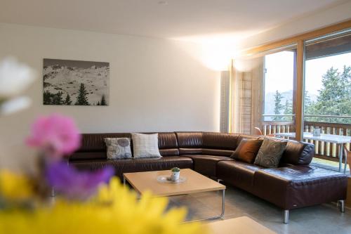 sala de estar con sofá de cuero marrón y mesa en Haus Bella Vista, en Riederalp
