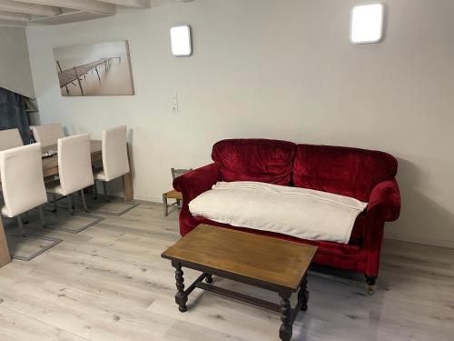 a living room with a red couch and a table at Maison à la campagne, proche de Carcassonne in Alairac