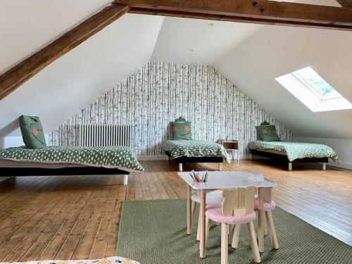 une chambre mansardée avec deux canapés et une table dans l'établissement Maison Fleurs de bobo, à Les Minières