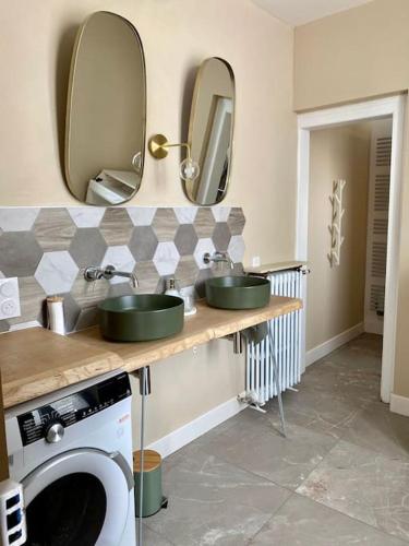une salle de bain avec deux lavabos et une machine à laver dans l'établissement Maison Fleurs de bobo, à Les Minières