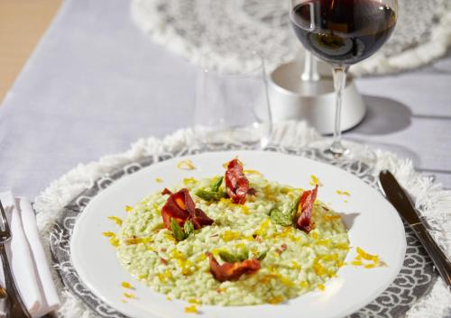 a plate of risotto with bacon and a glass of wine at Palace Hotel Zingonia in Verdellino