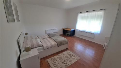 a white bedroom with a bed and a window at Barlang utca Villa in Cserszegtomaj