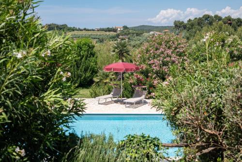 una piscina con 2 sillas y una sombrilla roja en La Muccheria, en San Vincenzo