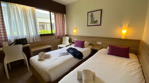 een hotelkamer met 2 bedden en een raam bij The Originals City, Le Logis d'Elbée, Cholet Nord (Inter-Hotel) in Beaupréau