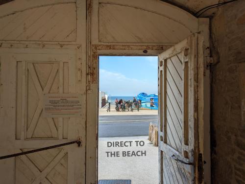 een deur met een bord dat direct naar het strand leest bij Charmante maison front de mer et centre ville in Luc-sur-Mer