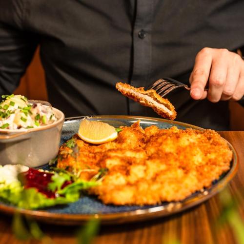 a person holding a fork and a plate of food at Mercure Katowice Centrum in Katowice