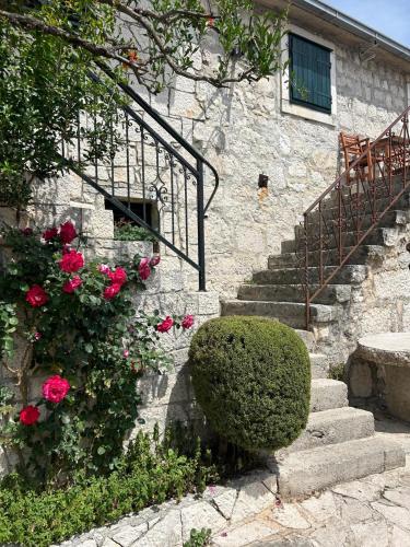 un edificio de piedra con escaleras y rosas rosas en Apartment Lovre Topic, en Baška Voda