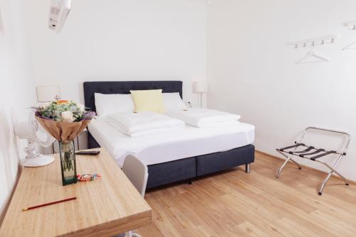 a bedroom with a bed and a table with flowers at Cityhotel am Domplatz Self-CheckIn in Klagenfurt
