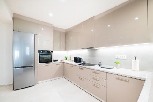 a kitchen with white cabinets and a refrigerator at THEA Seaview Luxury Living in Kalamata