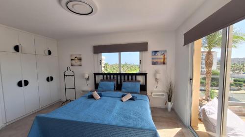 a bedroom with a blue bed and a large window at Nissi Golden Sands Paradi in Ayia Napa