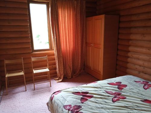 - une chambre avec un lit, une fenêtre et 2 chaises dans l'établissement Закарпатский сруб, à Krasna