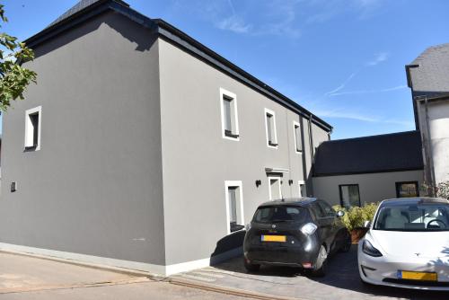two cars parked in front of a white building at Maison Activhome in Ospern