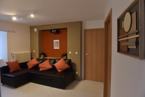 a living room with a black couch with orange pillows at Maison Activhome in Ospern