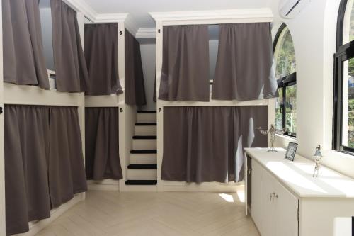 uma casa de banho com cortinas cinzentas e uma escada em Hotel Château Georgette em Pombas