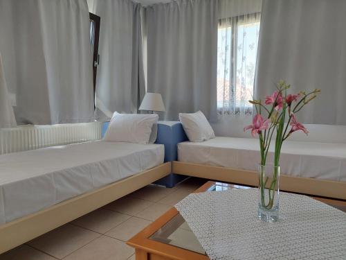 a living room with two beds and a vase of flowers at Dora's House comfortable apartment with a yard and view in Pyrgadikia