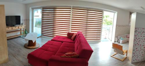 a red couch in a living room with a large window at Al Nido in Pietramurata