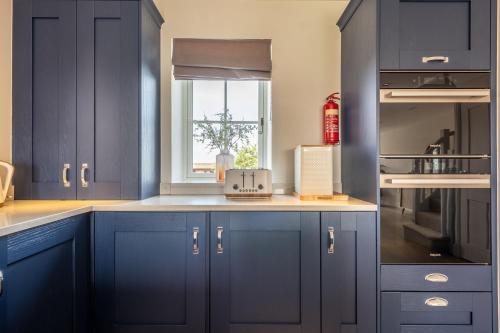 a kitchen with blue cabinets and a window at Kingfishers Cove in Titchwell