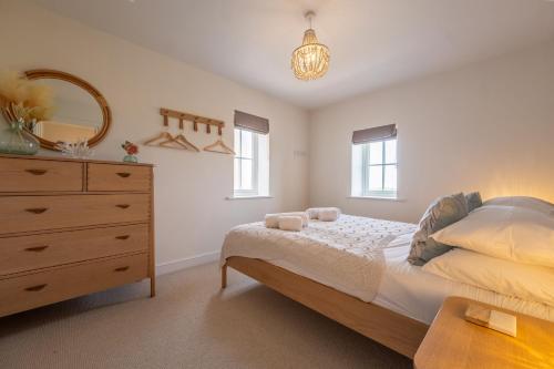 a bedroom with a bed and a dresser and a mirror at Kingfishers Cove in Titchwell