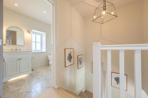 a bathroom with a staircase and a sink and a mirror at Kingfishers Cove in Titchwell