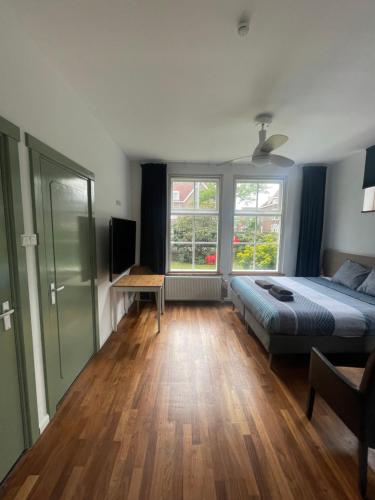 um quarto com uma cama, uma secretária e 2 janelas em B&B Bommelsteijn em Dordrecht