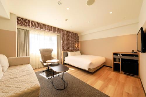 a hotel room with a bed and a couch at Richmond Hotel Matsumoto in Matsumoto