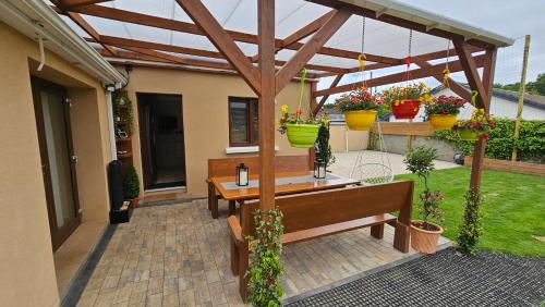a patio with a wooden pergola and a wooden bench at Killarney Cosy Hideaway in Killarney